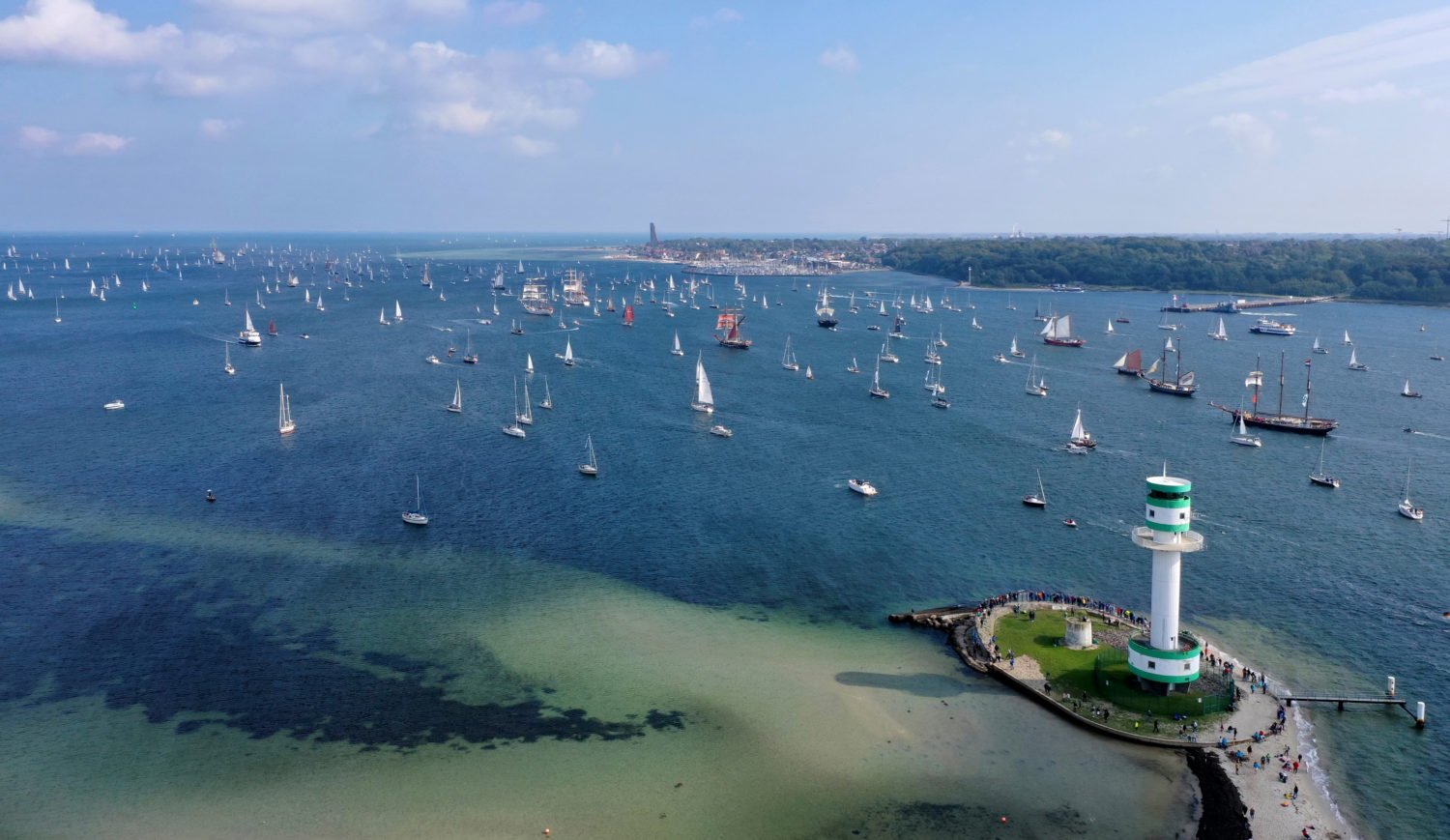 A parade of sails passes the Friedrichsort lighthouse